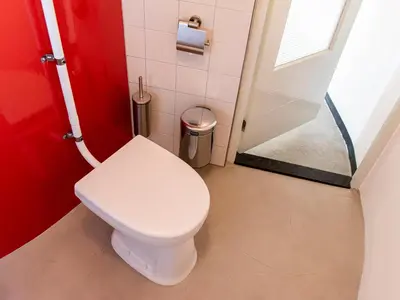 a white toilet in a bathroom with a red wall at SWEETS - Kortjewantsbrug in Amsterdam