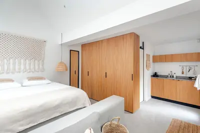 a bedroom with a large white bed and a kitchen at Suite-Suite luxury private guesthouse in Zandvoort