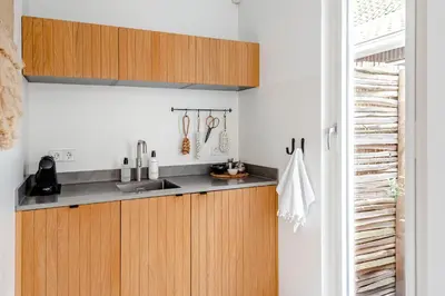 a kitchen with wooden cabinets and a sink at Suite-Suite luxury private guesthouse in Zandvoort