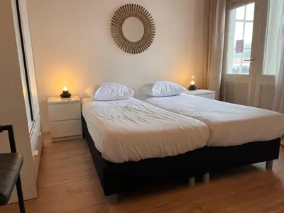a bedroom with a bed with two pillows and a mirror at Apartment Kerkplein 7A in Zandvoort