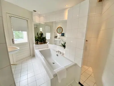 a white bathroom with a tub and a sink at Apartment Kerkplein 7A in Zandvoort