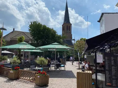 a street with tables and umbrellas and a clock tower at Apartment Kerkplein 7A in Zandvoort