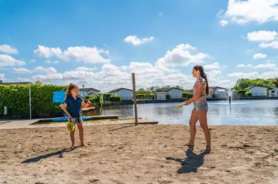two girls playing a game of frisbee on the beach at EuroParcs de Woudhoeve in Egmond aan den Hoef