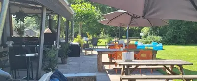 a patio with picnic tables and an umbrella at Rekerlanden 154 in Schoorldam