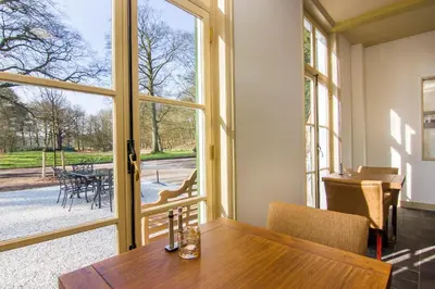 a dining room with a table and a large window at Gasterij Leyduin in Vogelenzang