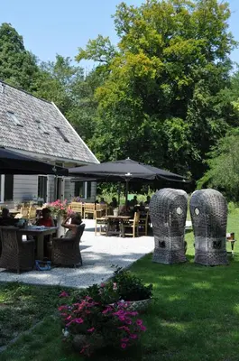 a patio with chairs and tables and an umbrella at Gasterij Leyduin in Vogelenzang