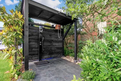 an outdoor shower with a black wall at Zandvoort Paradise Boutique Chambre in Zandvoort