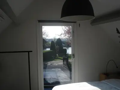a bedroom with a door leading to a patio at Aan de Vecht in Nederhorst den Berg