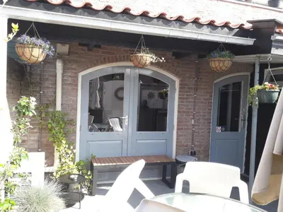 a patio with a blue door and white chairs at B&B CaSandra in Volendam