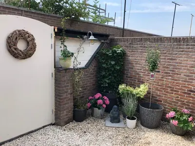 a garden with potted plants and a brick wall at B&B CaSandra in Volendam