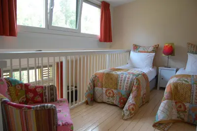 a bedroom with two beds and a chair and window at Lelymare Logies in Lelystad