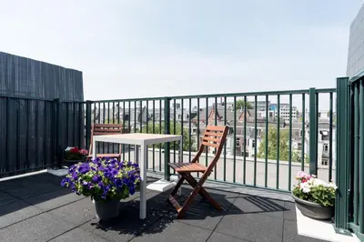 a balcony with a table and two chairs and flowers at Central Rooftop Terrace Guest Suite in Amsterdam