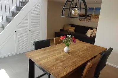 a dining room table with a vase of flowers on it at Albatros in Schoorl