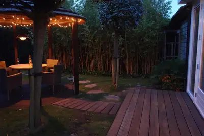 a backyard with a wooden deck with a table and trees at Albatros in Schoorl
