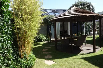 a gazebo with chairs and a table in a yard at Albatros in Schoorl