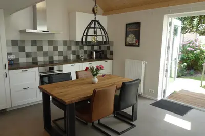a kitchen with a wooden table and some chairs at Albatros in Schoorl