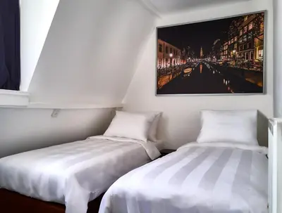 two beds in a room with a picture on the wall at Sleep Inn Amsterdam in Amsterdam
