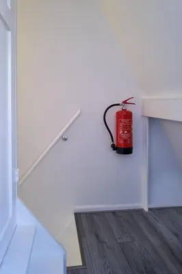 a fire hydrant sitting on the corner of a white wall at Sleep Inn Amsterdam in Amsterdam