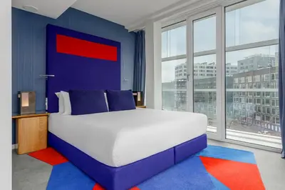 a bedroom with a large bed with blue walls and windows at Room Mate Aitana, Amsterdam in Amsterdam