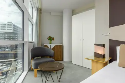a bedroom with a bed and a chair and a table at Room Mate Aitana, Amsterdam in Amsterdam