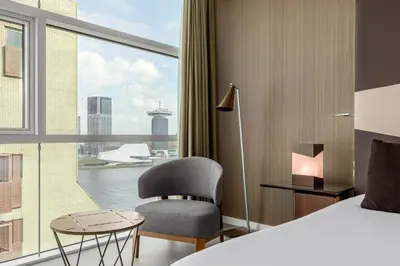 a hotel room with a bed and a chair and a window at Room Mate Aitana, Amsterdam in Amsterdam