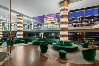 arium of a building with green seating and columns at Room Mate Aitana, Amsterdam in Amsterdam