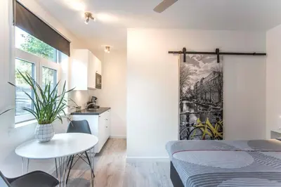 a bedroom with a bed and a table and a kitchen at Amsterdam Beach Zandvoort Studio s in Zandvoort