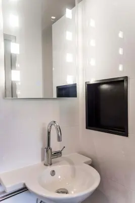 a white bathroom with a sink and a mirror at Amsterdam Beach Zandvoort Studio s in Zandvoort