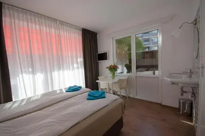 a bedroom with a bed and a sink and a window at Pension Oranje in Zandvoort