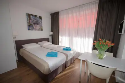 a hotel room with a bed and a table and a window at Pension Oranje in Zandvoort