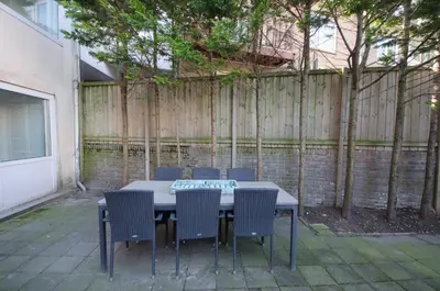 a table and chairs in a backyard with a fence at Pension Oranje in Zandvoort