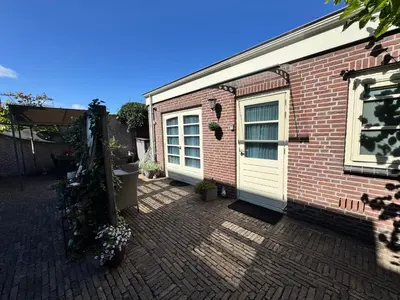 a brick house with a white door and a building at Appartement Villa Eva Rosa in Wijk aan Zee