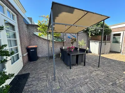 an umbrella over a table on a brick patio at Appartement Villa Eva Rosa in Wijk aan Zee