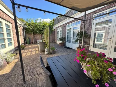 a patio with a wooden table and flowers at Appartement Villa Eva Rosa in Wijk aan Zee