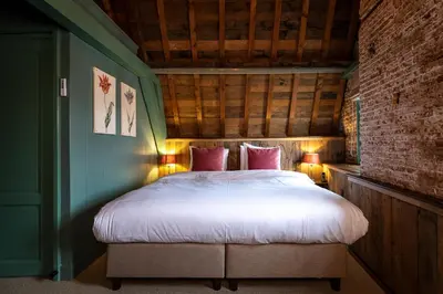 a bedroom with a bed with white sheets and pink pillows at Hotel Beijers in Utrecht