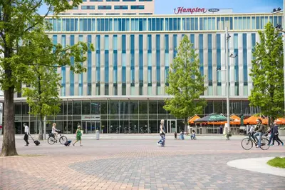 people walking and riding bikes in front of a building at Hampton By Hilton Amsterdam Arena Boulevard in Amsterdam