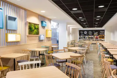 a dining room with wooden tables and chairs at Hampton By Hilton Amsterdam Arena Boulevard in Amsterdam