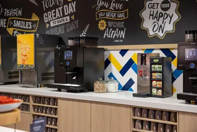 a coffee shop with a counter with a coffee station at Hampton By Hilton Amsterdam Arena Boulevard in Amsterdam