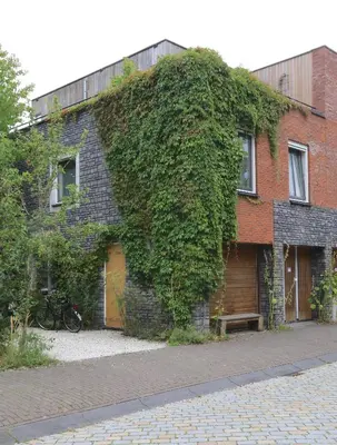 an ivy covered brick building with a wooden garage at B&B De Zwanebloem in Amsterdam