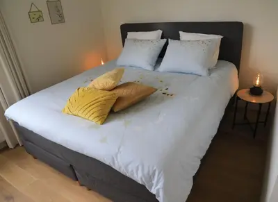 a bed with white sheets and pillows with a candle on it at B&B De Zwanebloem in Amsterdam