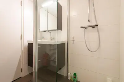 a shower with a glass door next to a sink at Quiet apartment for 4 at park in center in Amsterdam