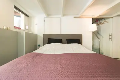 a bedroom with a bed with a pink blanket at Quiet apartment for 4 at park in center in Amsterdam
