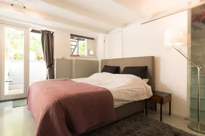 a white bedroom with a bed and a window at Quiet apartment for 4 at park in center in Amsterdam