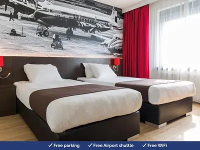 two beds in a hotel room with a picture on the wall at Bastion Hotel Amsterdam Airport in Hoofddorp