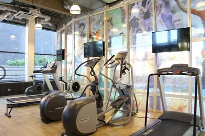 a gym with cardio machines and a wall with a mural at Bastion Hotel Amsterdam Airport in Hoofddorp