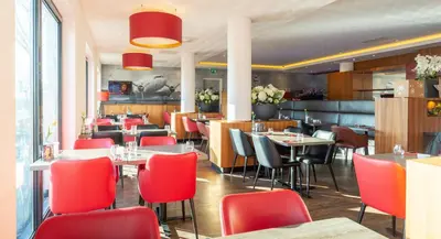 a restaurant with red chairs and tables in a room at Bastion Hotel Amsterdam Airport in Hoofddorp