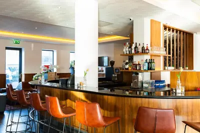 a bar in a restaurant with brown chairs at Bastion Hotel Amsterdam Airport in Hoofddorp