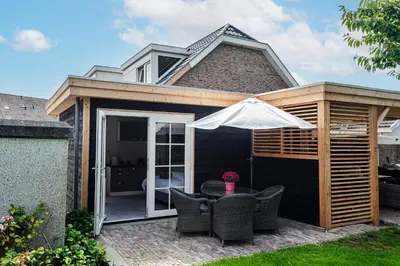 a pergola with chairs and an umbrella on a patio at Studio Pit-Stop in Zandvoort