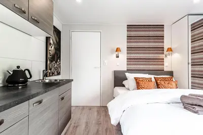 a bedroom with a large white bed and a sink at Studio Pit-Stop in Zandvoort