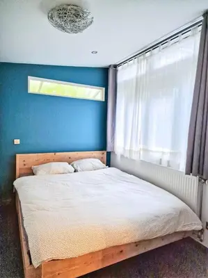 a bedroom with a bed with a blue wall and a window at A cozy place in Amsterdam in Amsterdam